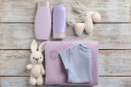 木制背景上的婴儿服装沐浴化妆品毛巾和玩具图片