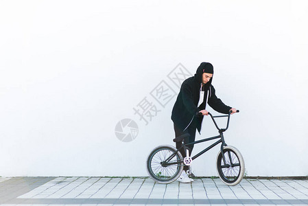 白墙背景下骑自行车者bmx的肖像有一辆自行车的Bmx车手在白色背图片