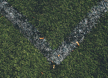 足球Fierld角绿色合成草坪橄榄球的白线涂料贴近角图片