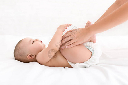 母亲在床上按摩新生婴儿加强婴儿锻炼图片