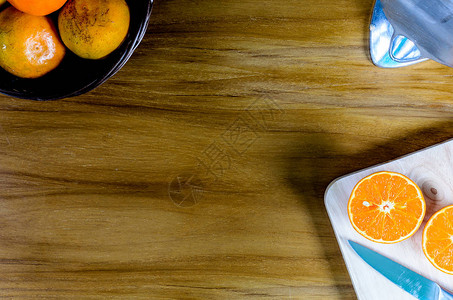 木块上用刀切的橙子木桌上的柳条棕色篮子图片