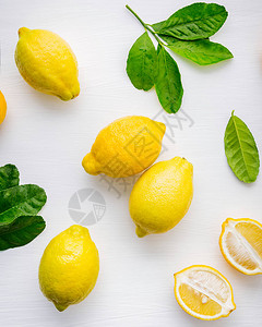 新鲜的柠檬和柠檬叶在白色木制背景上图片