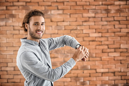 带手表的年轻人在砖背景图片