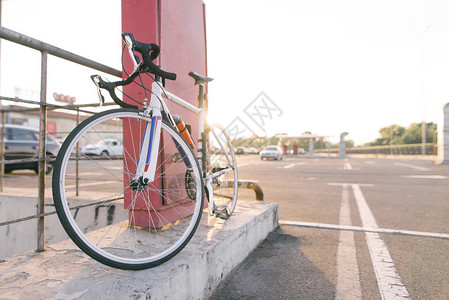 在汽车的街道停车的背景的白色公路自行车生态运输体育概念自行图片