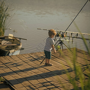 小男孩学会在湖泊或河流中捕鱼有钓鱼竿的孩子在木码头暑假图片