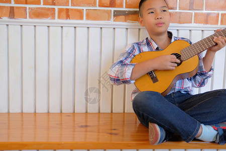 亚洲儿童男孩在家弹吉他尤克里儿童休闲活动图片