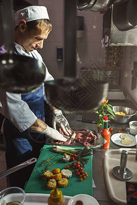 为沙拉准备蔬菜在专业旅馆或餐厅厨房调制新鲜牛肉排的男厨师图片