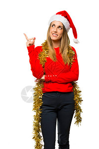 金发女人穿着衣服去过圣诞节手指着一个好点子仰望着孤立的白种图片