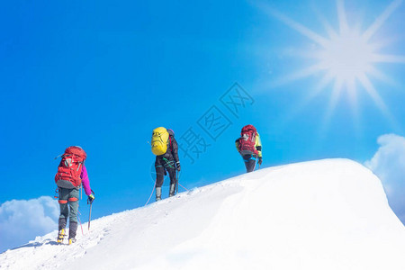 登山者在阳光明媚的冬天到达雪山顶图片