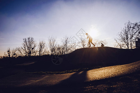 日落时滑板公园里滑板车滑板和自行车图片