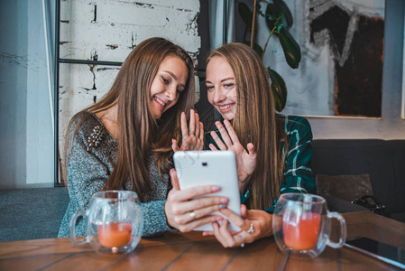 两名年轻美女用平板电脑通过视频聊天交谈图片