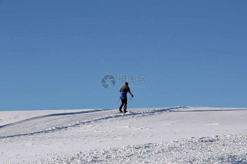 一位越野滑雪者在冬天反对蓝天越野滑雪是一项流图片