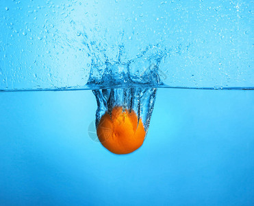 橘子在彩色背景下落入水中图片