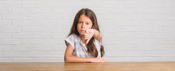 坐在桌子上坐在家里的年轻西班牙小孩看着不开心和愤怒图片