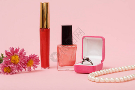 指甲油口红珠子和粉红色背景的鲜花图片