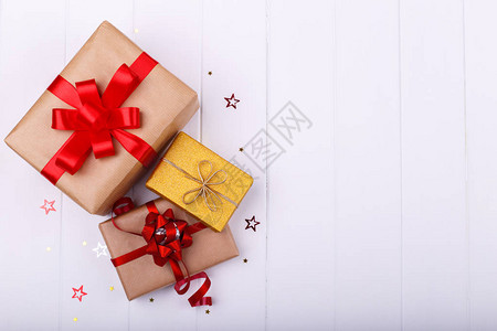 白色木背景的3个礼品盒纸红丝带图片