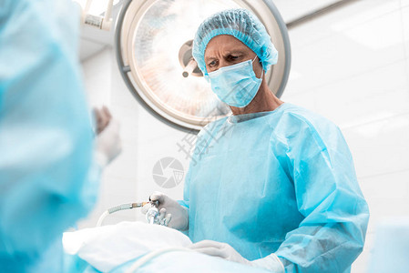 在外科手术期间使用腹腔镜形器的无菌蓝礼服和帽子图片
