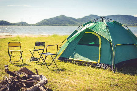 野营帐篷与熄灭的篝火在绿色的田野草甸湖泊和山脉背景野餐和旅行的概背景图片