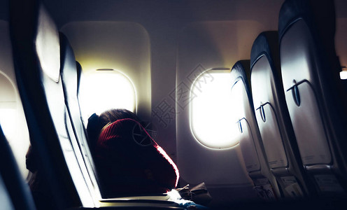 疲惫的休闲无法辨认的千禧一代白种年轻女子在坐飞机旅行时在座位上打盹小憩高清图片素材