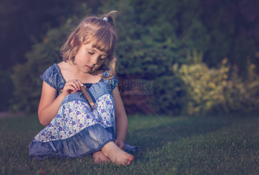 赤脚身穿蓝裙子坐在草地上抱着图片