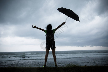 海边风雨中撑伞的女人图片
