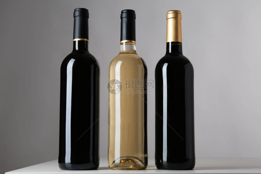 灰色背景中装有不同种类葡萄酒的瓶子图片