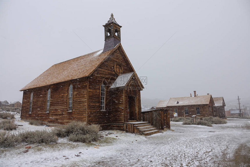 来自加利福尼亚淘金热的田园诗般的废弃采矿小镇的古老木制教堂被新鲜的雪覆盖在寒冷的美国荒野中拍摄如图片