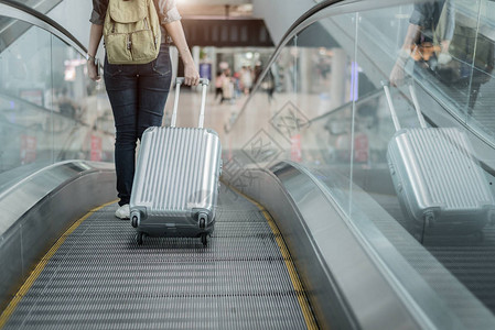 带着行李箱乘飞机去世界各地的女旅行者的下半身特写机场航站楼自动扶图片