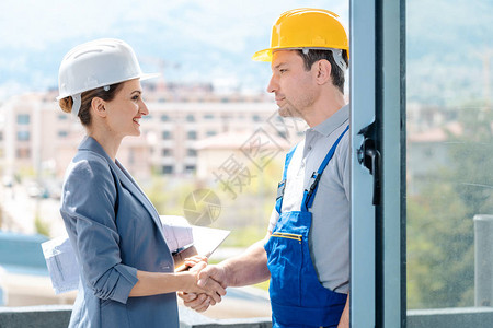 开发商和建筑商之间在施工地上握手以接受背景图片