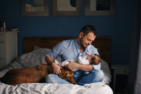 中年白种人父亲与刚出生的婴儿的画像狗宠物躺在床上男人父母手里拿着孩子真实的生活方式纪录片时刻单亲爸背景图片