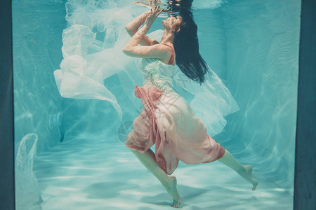 穿着女长白色和粉红白裙子在水下游泳图片