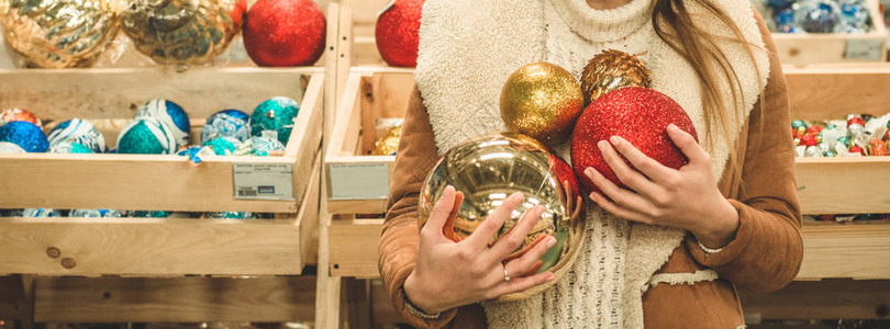 穿着温暖大衣的女孩拿着大球在圣诞节展会的购物中心为圣诞树盛宴举办图片