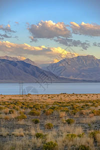 与山和天空在犹他湖的美丽景色美丽的风景与雄伟的山脉和壮丽的天空在犹他湖超出草湖岸边多云的天空在日落时散发背景图片