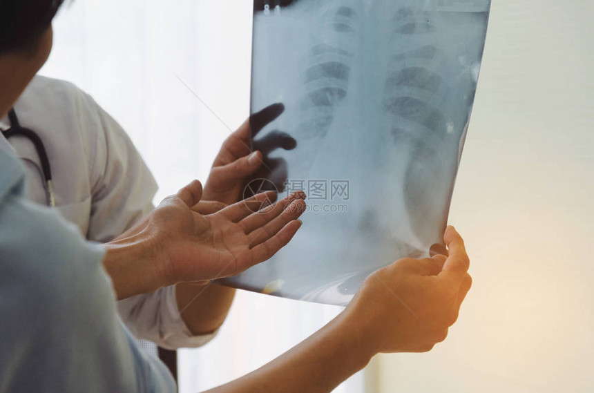有医生在胸部X光片上展示和检查关于医院病人健康问题办公室综合症保健医疗医学药学概念的图片