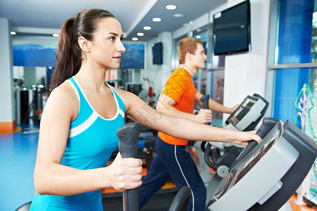 在健身房进行有氧训练男女在运动俱乐部的交叉训练机上图片