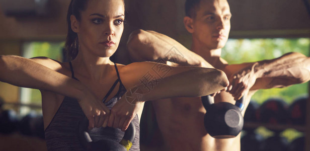 使用铁重量在健身房工作的健康运动和运动的人男人和女人用哑铃训练体育田图片