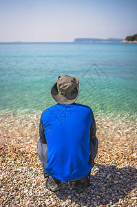 身戴帽子站在沙滩上观光的游客看着杜布罗夫尼克令人惊叹的图片