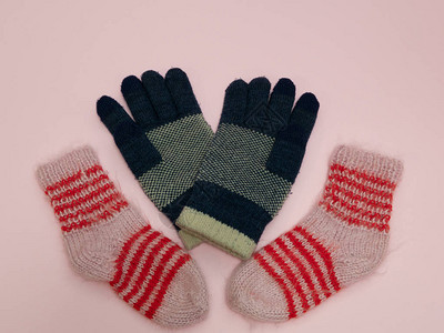 一对羊绒袜子和粉红色背景的手套冬图片