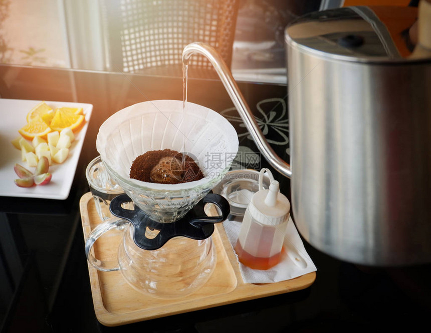 滴滤咖啡师将水倒在过滤咖啡上滴滤制作杯子手滴咖啡过滤在托盘木黑桌咖啡店的玻璃罐中图片
