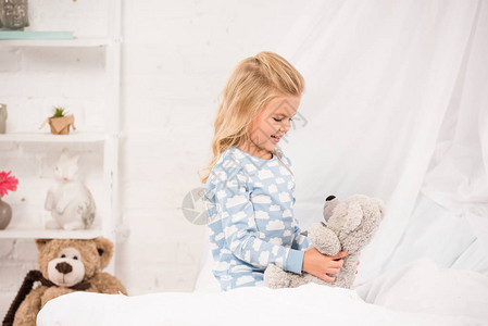 快乐的孩子在床上和泰迪熊玩耍背景图片