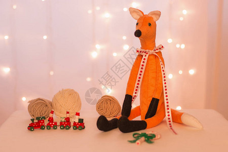 手工制作的红狐坐在圣诞灯球木火车和图片