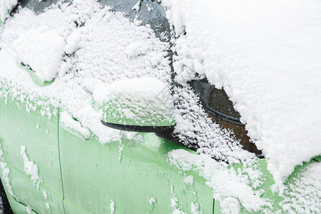 大雪天白雪覆盖的绿色汽车驾驶安全概念图片