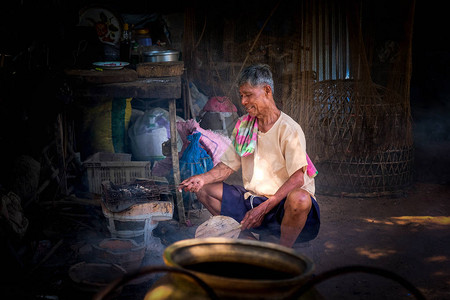 泰国农村的老人们正在炭炉里烤鱼图片