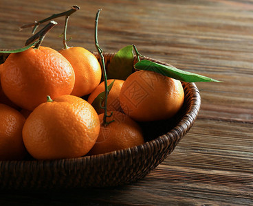 木桌上有美味橘子的柳条托盘图片
