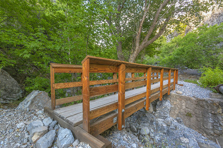 在普罗沃犹他州一座落基山上的木桥犹他州普罗沃一座落基山上一条狭窄溪流上的木桥从这条远足小径可以看到茂密的树木和明亮的阳背景图片