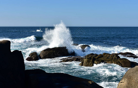 大浪冲向岩石和渔船图片