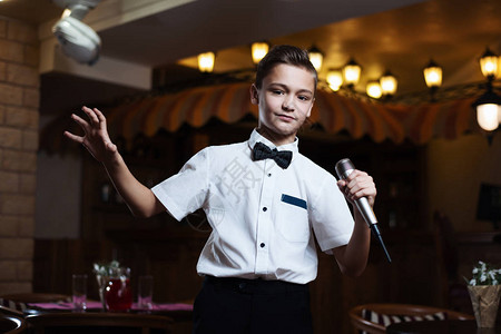 一个穿白衬衫的男孩在餐馆的麦克风里唱歌背景图片