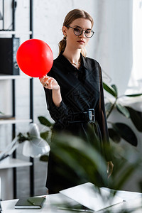 穿着黑衣服的漂亮女人拿着红气球看摄影背景图片