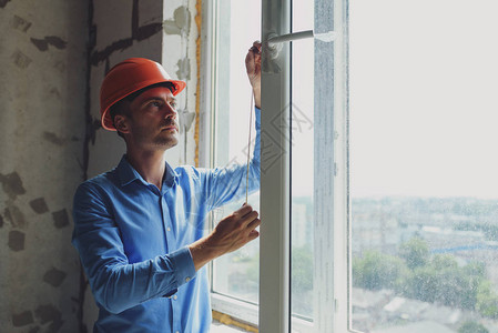 建筑工地窗户安装中的男工业建筑工人图片