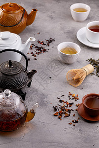 茶卡灰色背景的茶壶和杯子以及不同种类的茶背景图片